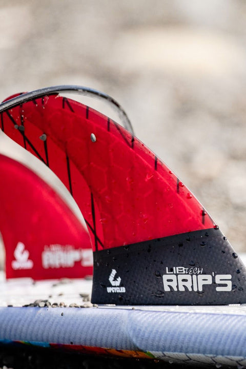 Lib Tech Twin + Mini Trailer - Red - Closeup of forward fins on a board with a leash wrapped around the top of it.