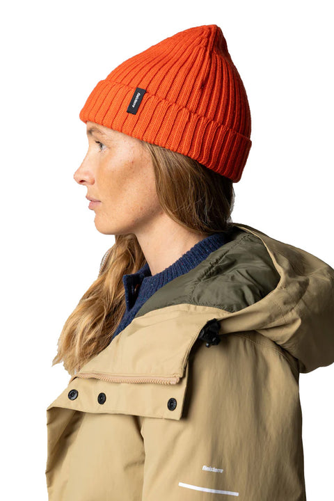 Person wearing an orange beanie and beige coat on a white background