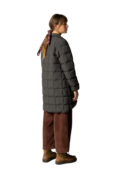 Person wearing a long puffer coat and brown pants on a white background