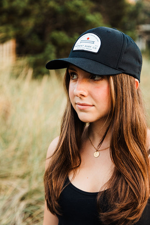 Woman wearing a black cap with a logo outdoors