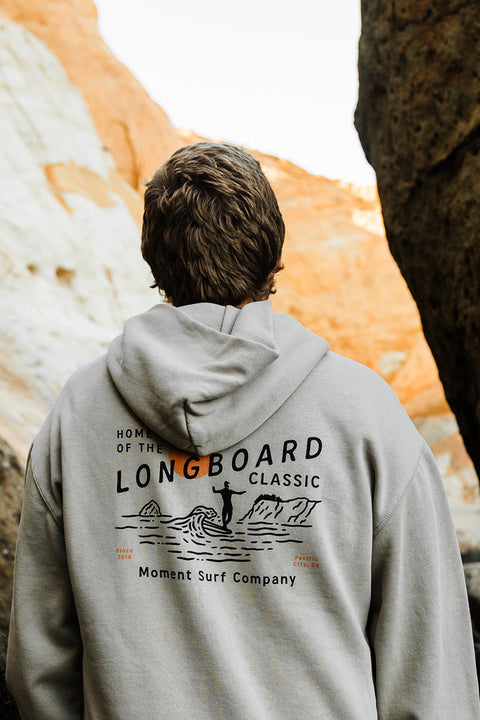 Person wearing the Moment The Classic Pullover Hoodie - Faded Taupe, standing in front of rocky cliffs.