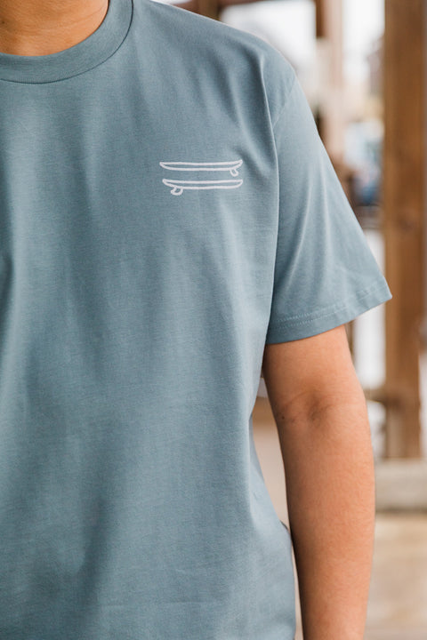 Person wearing a teal t-shirt with a white logo on a blurred background