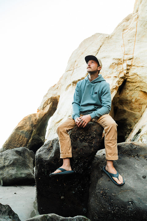 Man sitting on a rock by large coastal cliffs
