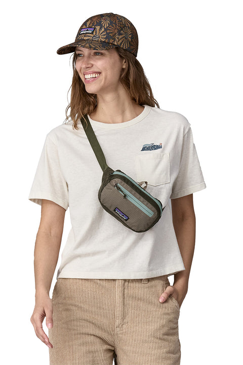 Patagonia Ultralight Black Hole Mini Hip Pack - Pine Needle Green- Slung over models shoulder