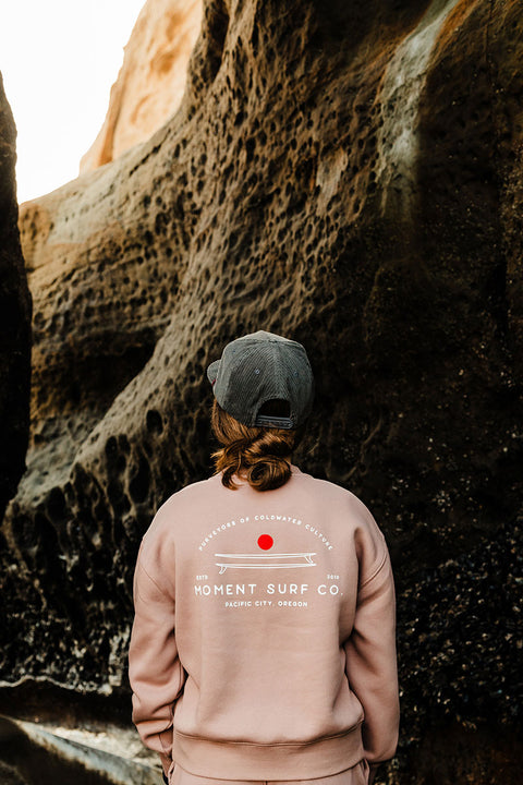 Moment Women's Board Stack Pullover Crew - Hazy Pink - Model facing away from the camera looking at a canyon.