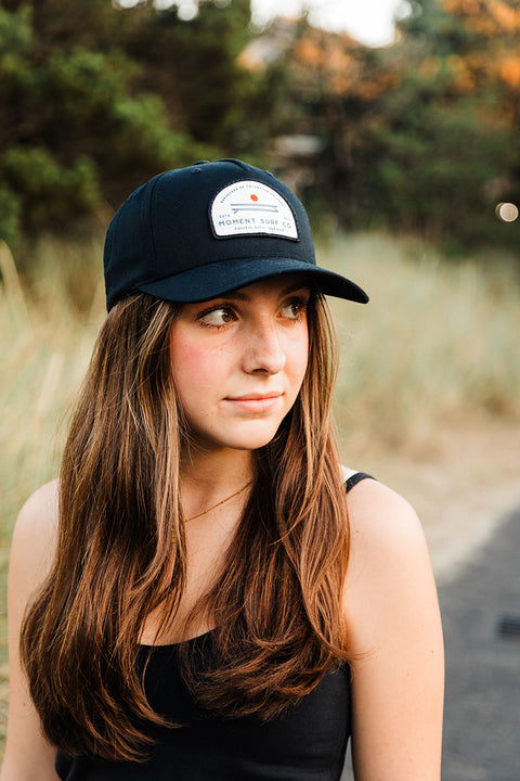 Woman wearing a black cap with a white patch outdoors