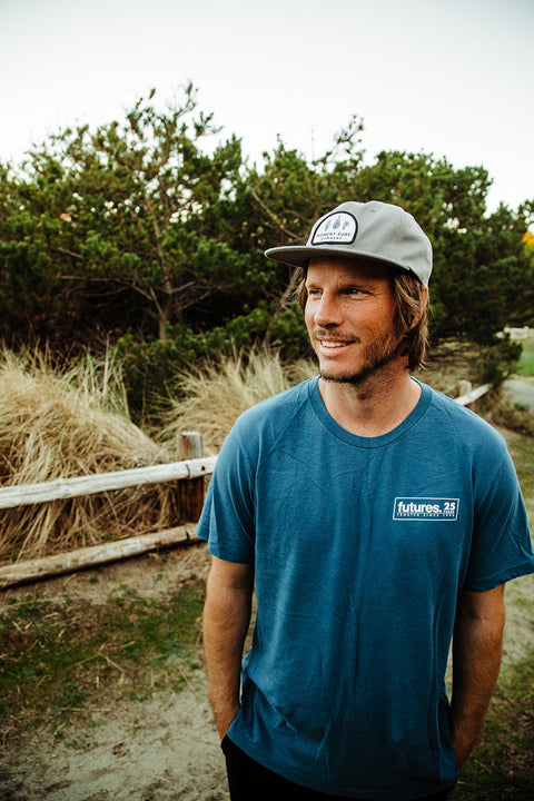 A male model looking to the right wearing the Moment Kelp Friends 5 Panel Hat.