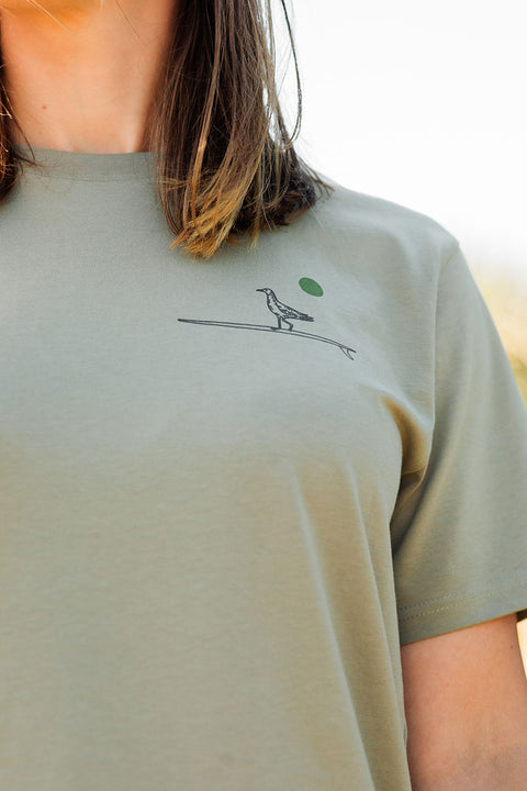 Person wearing the Moment Women's Lt Dan T-Shirt - Eucalyptus facing toward the camera, zoomed in on the logo
