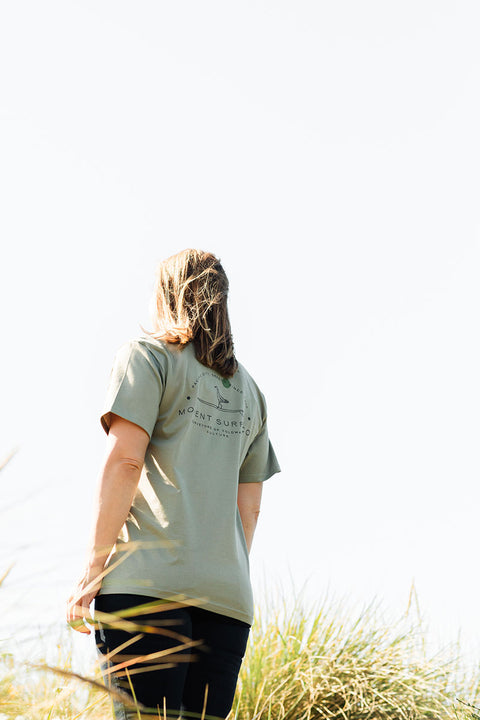 Person wearing the Moment Women's Lt Dan T-Shirt - Eucalyptus facing away from the camera looking at the sky.