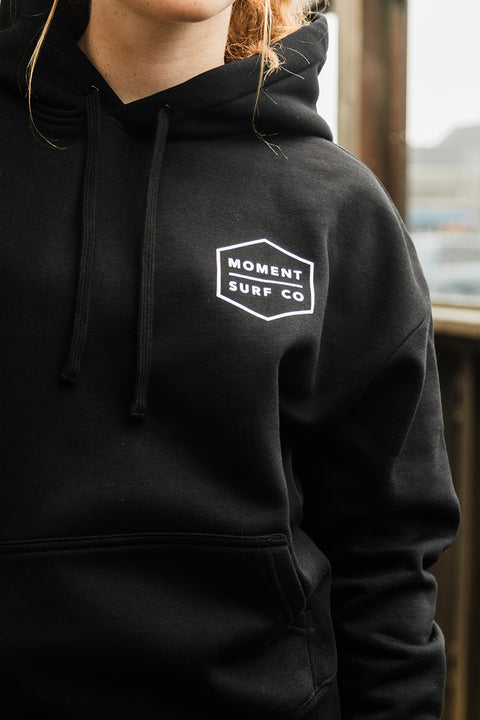 Moment Women's Boxed Topo Logo Pullover Hoodie - Black / Multi closeup of front chest hoodie logo