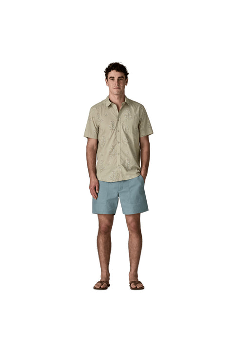 Man wearing a beige shirt and light blue shorts on a white background